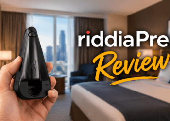 A person holding the black riddiaPress cordless travel iron in a hotel room.